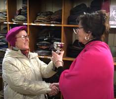 Giving back of now-engraved trophy for Best Christmas Shop Window 2023 (from Bridport Christmas Cheer) - by Jill of the TUC to Sue of T Snook, hat shop of Bridport