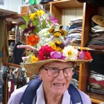 Visitor in flowers hat to T Snook hat shop in Dorset UK during Bridport Hat Festival 2023