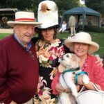 Roger Snook, Sue Darling, and Monica Snook with Tuppence the dog, all of T Snook hat shop in Dorset UK, during Bridport Hat Festival 2023