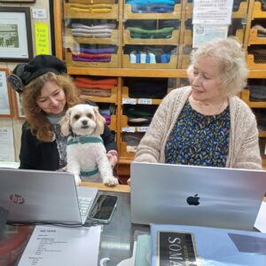 Shop dog Tuppence helps with admin at T Snook hat shop in Bridport Dorset UK